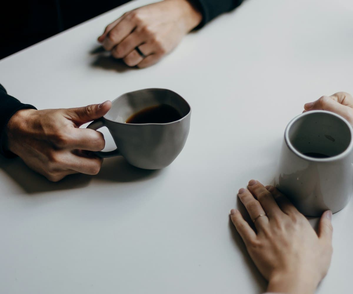 Asesor y cliente conversando con un café sobre la mesa